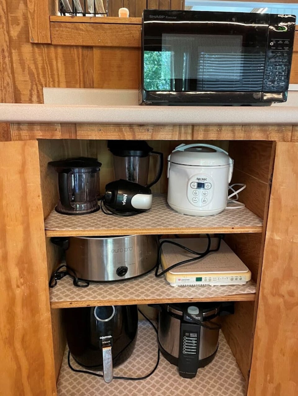 Fully equipped kitchen nook with microwave, blender, rice cooker, air fryer, and slow cooker.