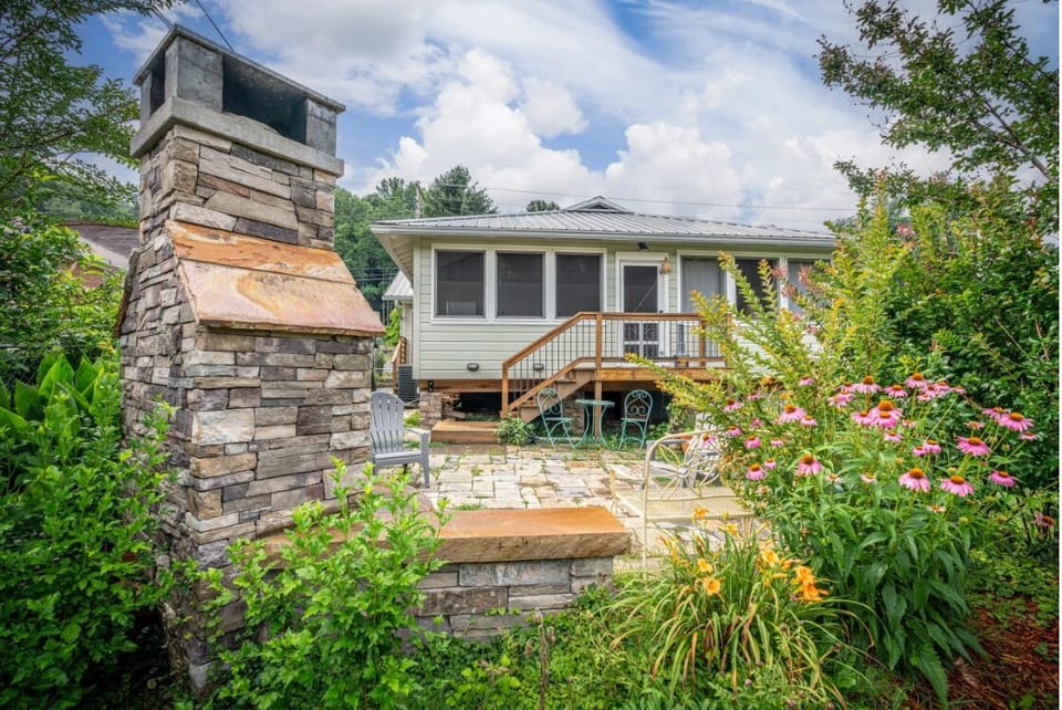 Side view of BC Downtown Villa showcasing the charming architecture, stacked-stone chimney, and colorful garden landscaping that surrounds this Bryson City vacation home.
