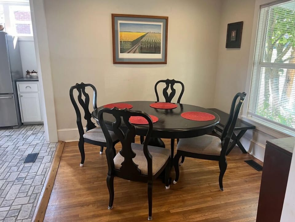 Dining area at BC Downtown Villa featuring a round table set for four beside a large window, offering a cozy place for family meals near downtown Bryson City.