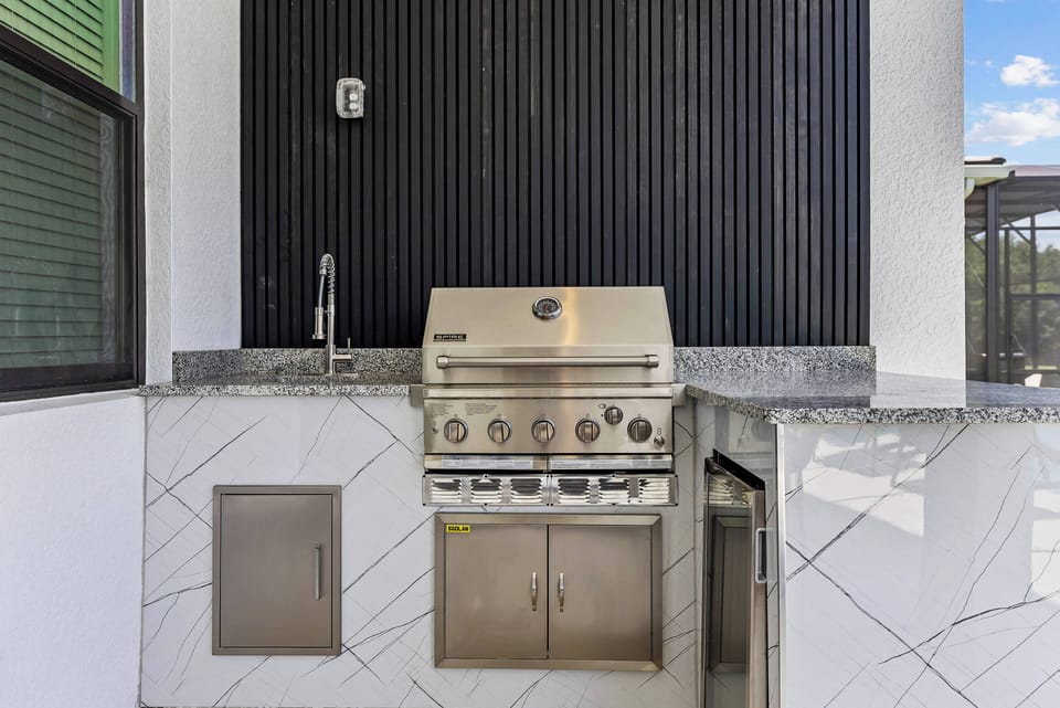 Enjoy outdoor cooking with a sleek stainless steel grill on a stunning black panel. The elegant marble countertop makes meal prep a pleasure, perfect for gatherings or relaxing evenings in the fresh air.
