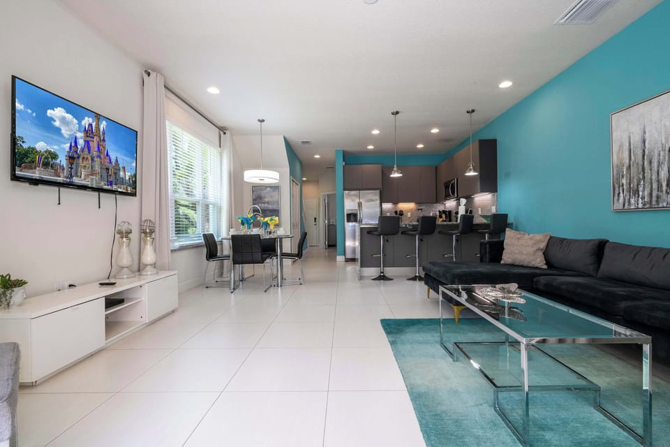 Relax in our open-concept living area featuring a plush accent sofa, turquoise feature wall, and wide windows that flood the space with natural light.