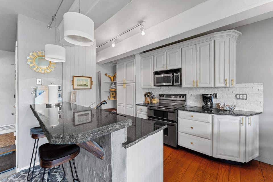 Full kitchen featuring upgraded countertops, stainless steel appliances, and breakfast bar seating 2.
