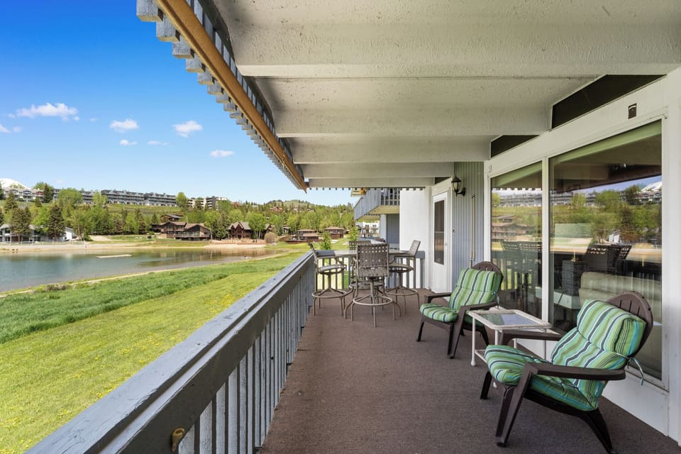Relax on your private lakefront balcony with comfortable seating and dining space, overlooking peaceful waters and green lawns.