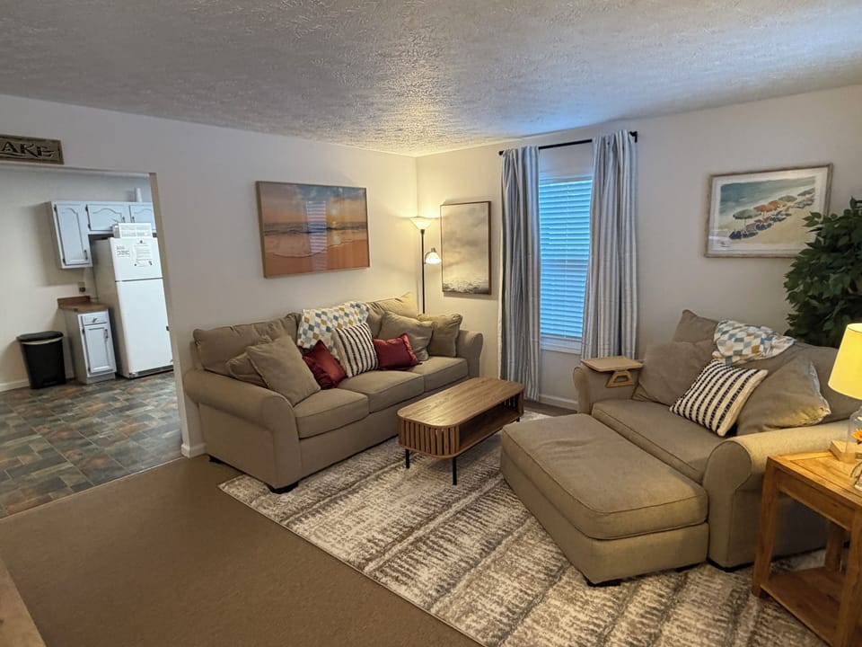 Cozy living room with plush seating, stylish decor, and open kitchen access.