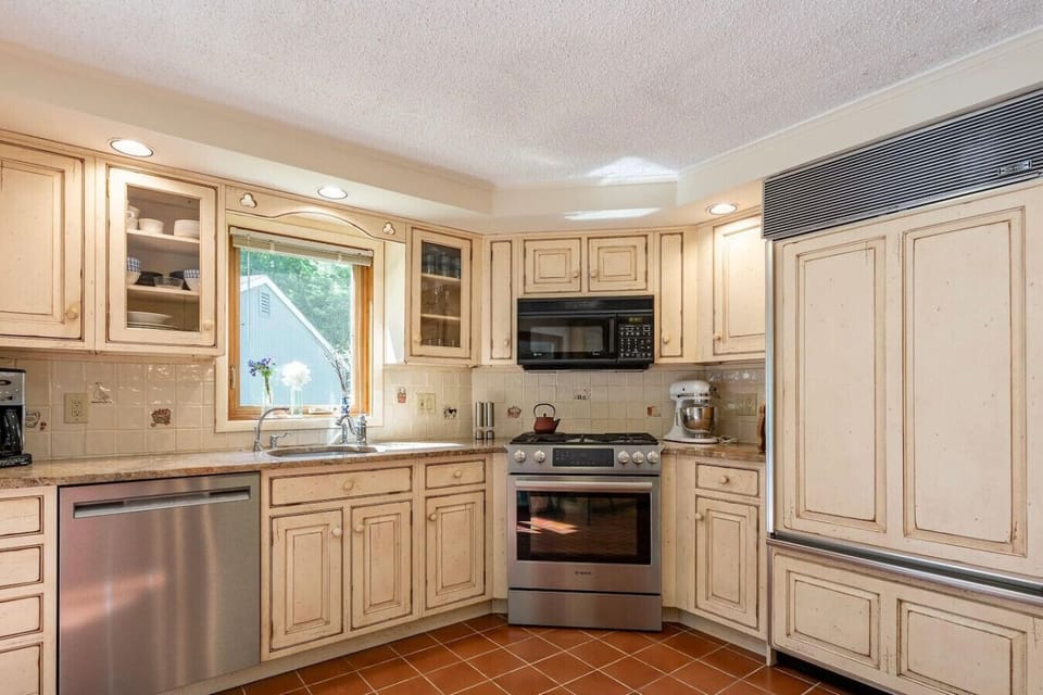 Fully equipped kitchen with cream cabinetry, stainless steel appliances, and window over sink.