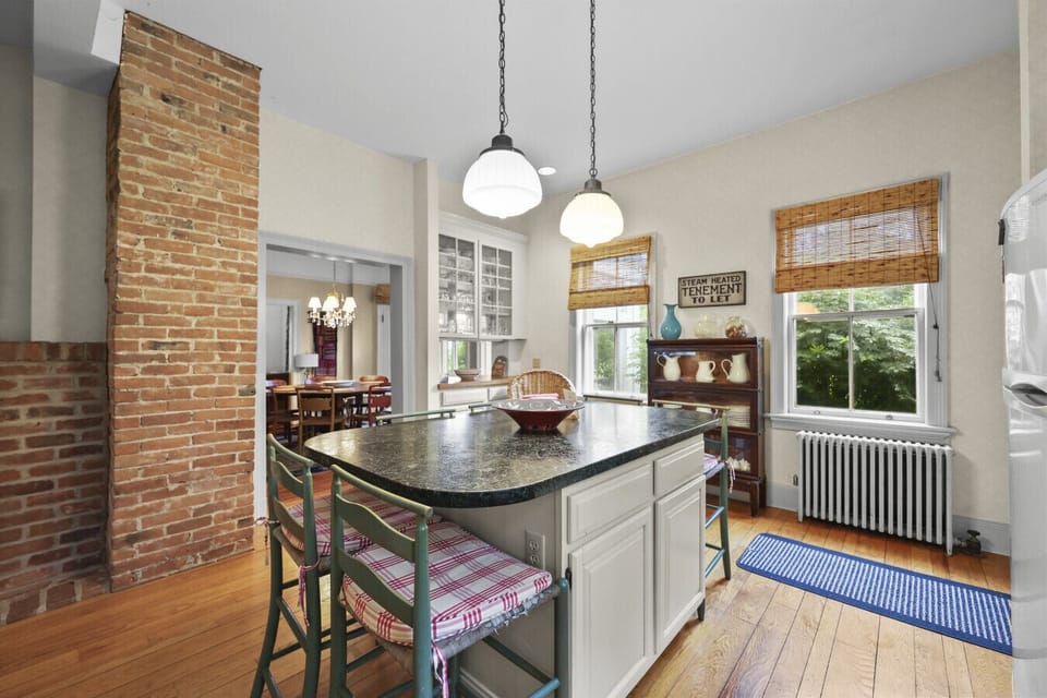 Open kitchen with island seating and charming brick accent.