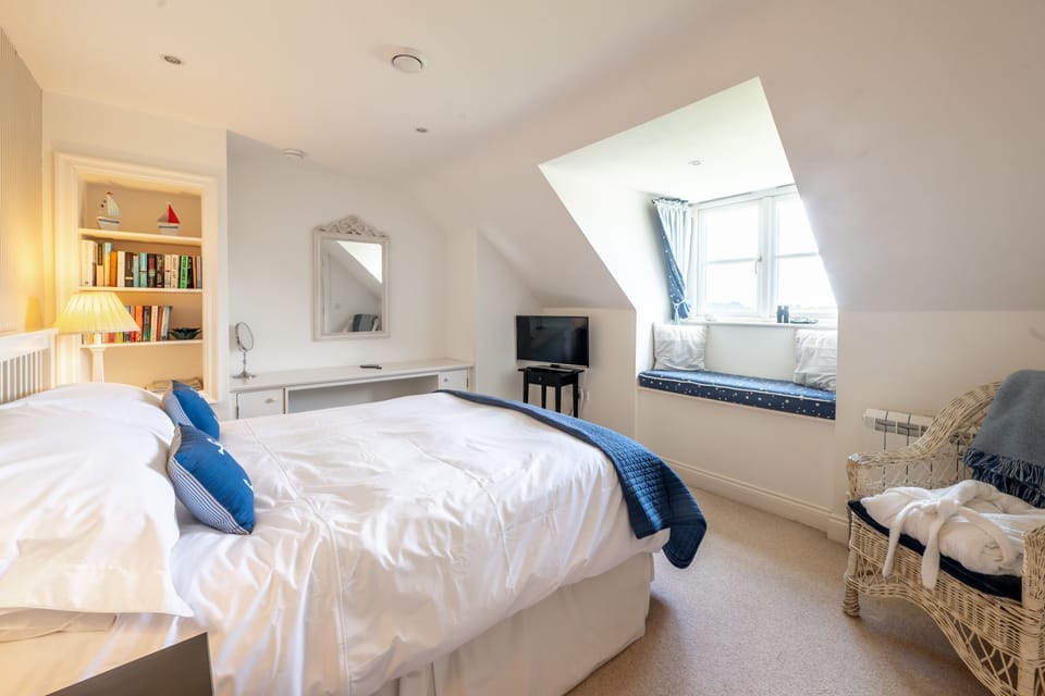 Second floor: Master bedroom with a 5' king-size bed, armchair, matching bedside tables and lamps, hairdryer, dressing table with a stool, television, and a window seat with sea views