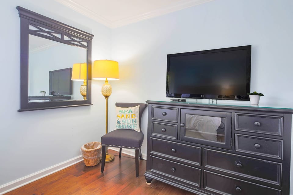 The guest bedroom also features a dresser with a wall-mounted smart TV.