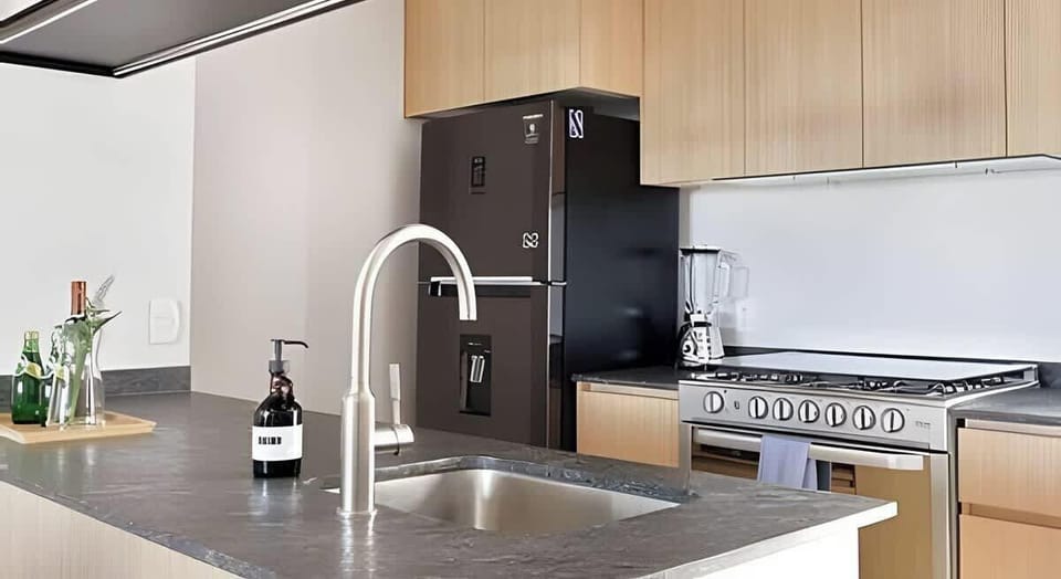 Sleek kitchen counter w/ sink, stovetop & warm wood cabinetry