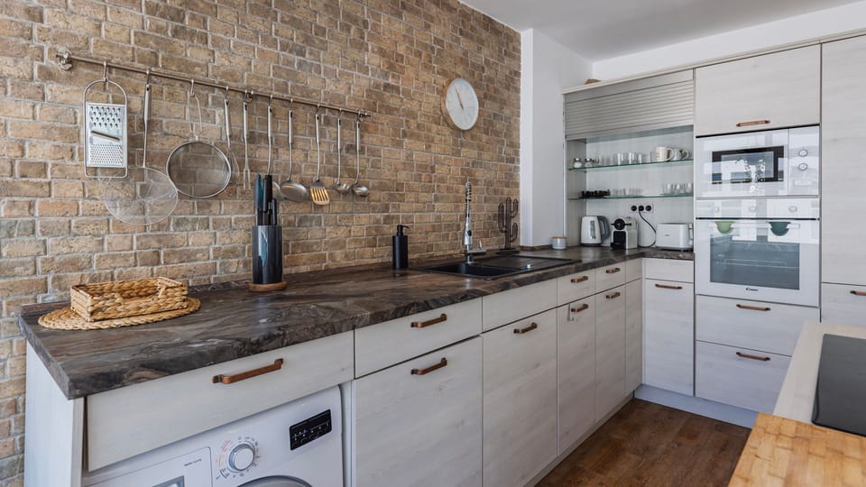 Cook in style with this contemporary kitchen featuring stone countertops, rustic brick walls, built-in appliances, and modern cookware.
#ModernKitchen #Portugal #PT #CostaDaCaparica