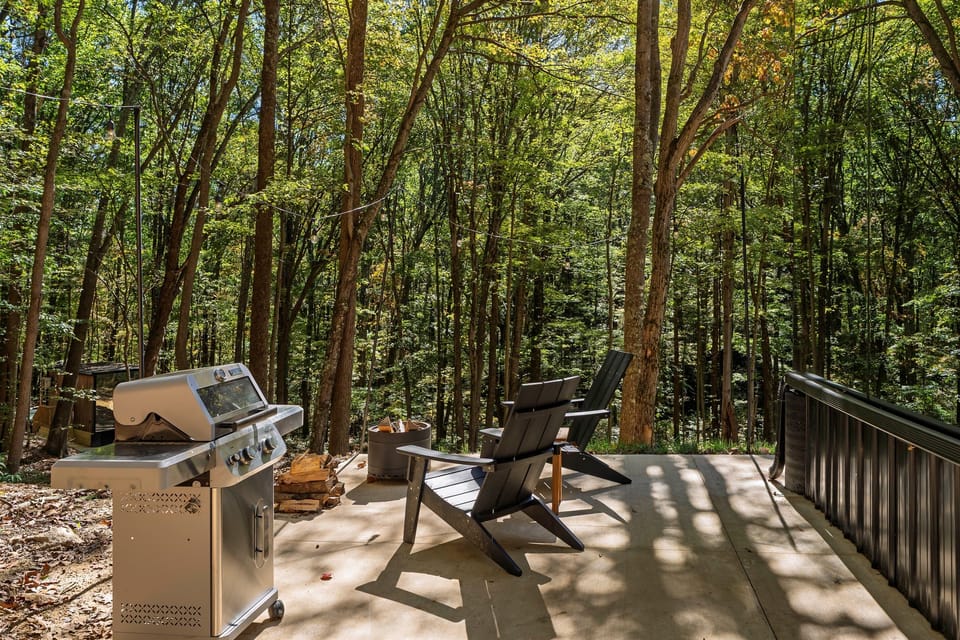 Outdoor patio at Muir — propane grill, Adirondack seating, wooded surroundings, elevated position on the hillside