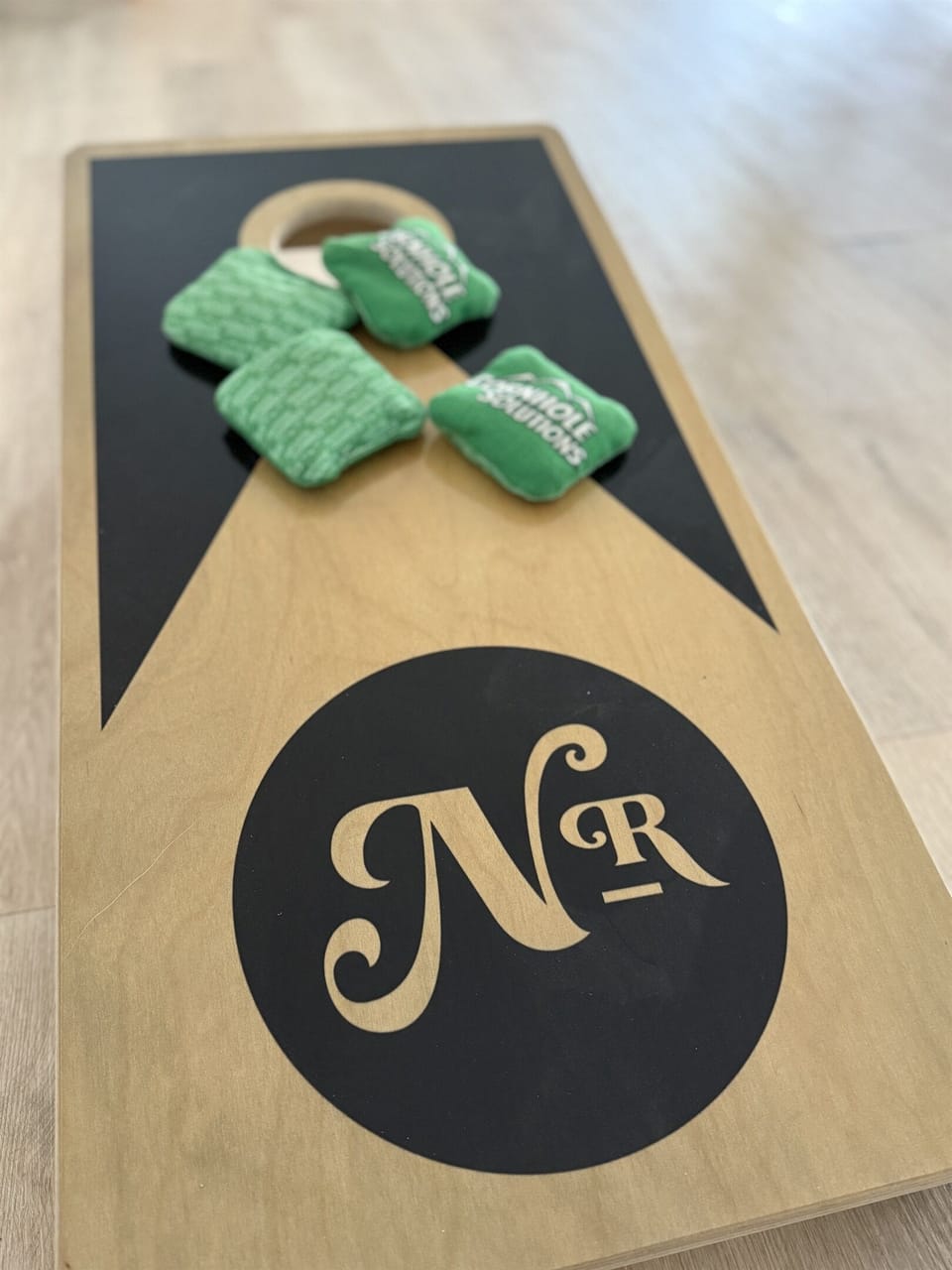 Indoor cornhole in the shared game room — Notestone Reserve branded, separate building a short walk from Muir