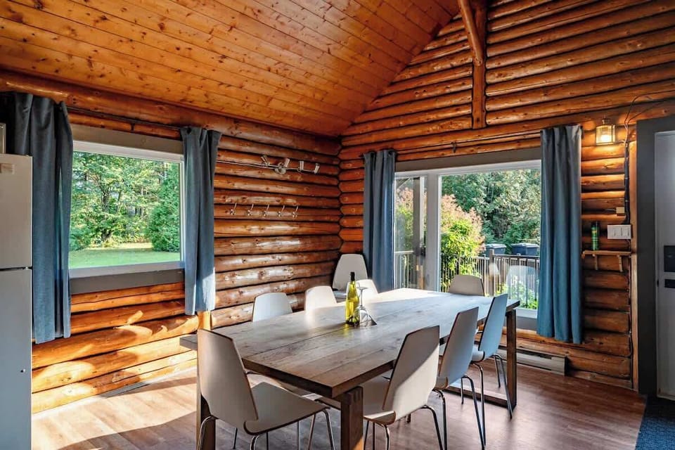 Bright dining area with large windows offering views of the lush outdoor space.