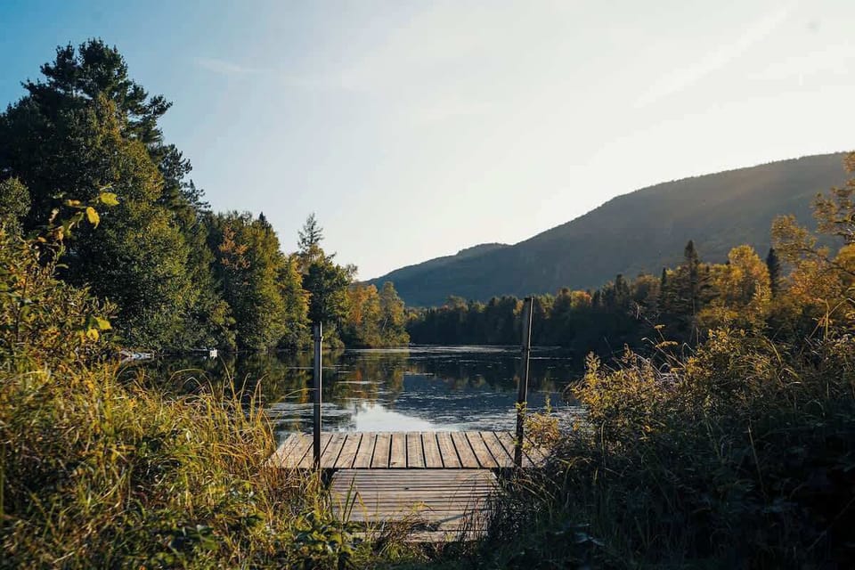 Serene dock by the water, surrounded by vibrant nature and mountain views, perfect for unwinding.