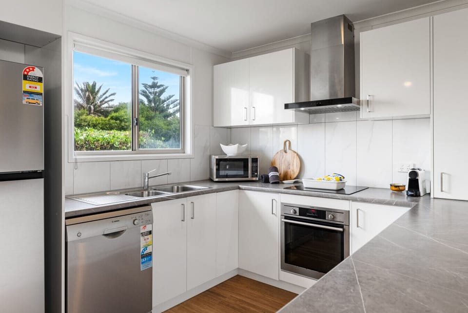 Start the day in the kitchen, where generous bench space and modern appliances make preparing breakfast before a beach walk simple and social.