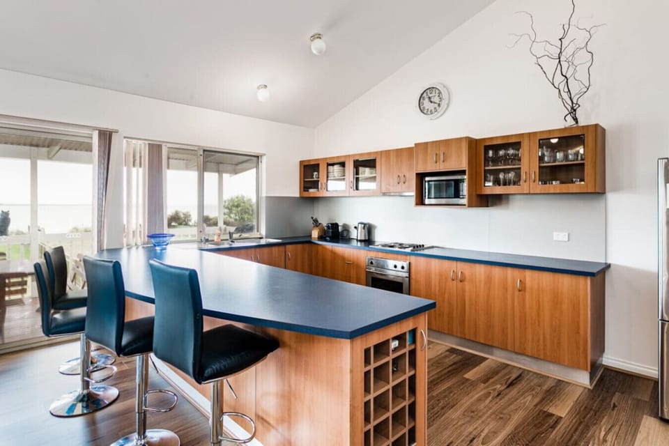 Cook meals in the fully-equipped kitchen with timber cabinetry, island bench seating, and modern appliances.