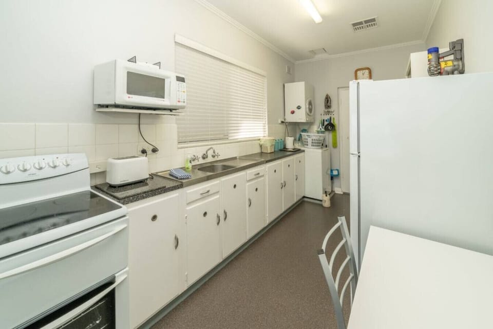 Prepare meals in the retro 1960s kitchen equipped with a stove, microwave, refrigerator, toaster, kettle, and generous bench space, making it easy to cook before heading out for a beach walk.