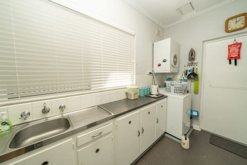 Move through to the back of the kitchen where a double sink, washing machine, and everyday appliances make longer stays feel easy and self-sufficient.
