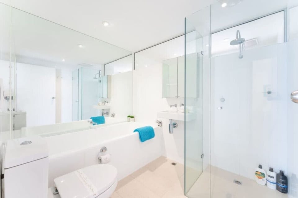 Refresh and reset in the bright family bathroom with a glass shower, full bathtub, and fresh pops of turquoise for a modern coastal feel.