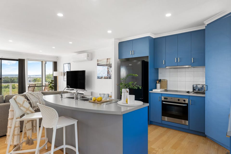 Bright kitchen setup with full appliances, ample bench space, and garden views.