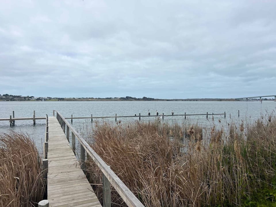 The timber jetty stretches into the calm waters, offering a serene place to relax and enjoy the scenery.