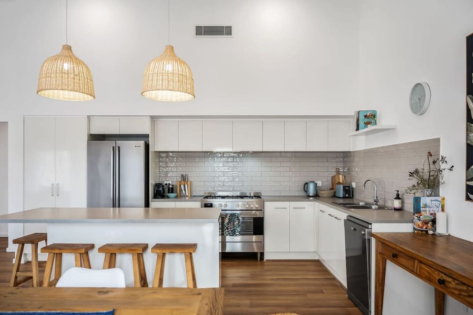 The modern kitchen is equipped with a breakfast bar, pendant lighting, and stainless steel appliances.