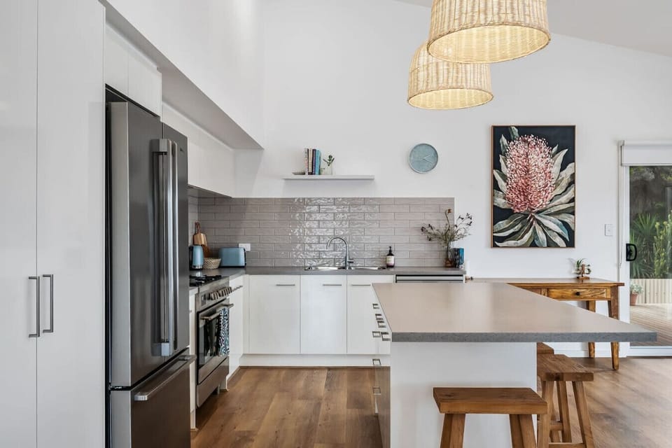 Sleek white cabinetry and wood accents paired with subtle tile finishes and natural light round out the kitchen.