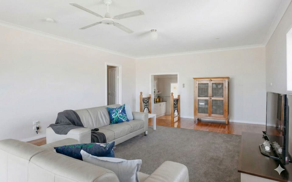 The living area centres around a central TV, with leather lounges, ceiling fans and cooling.