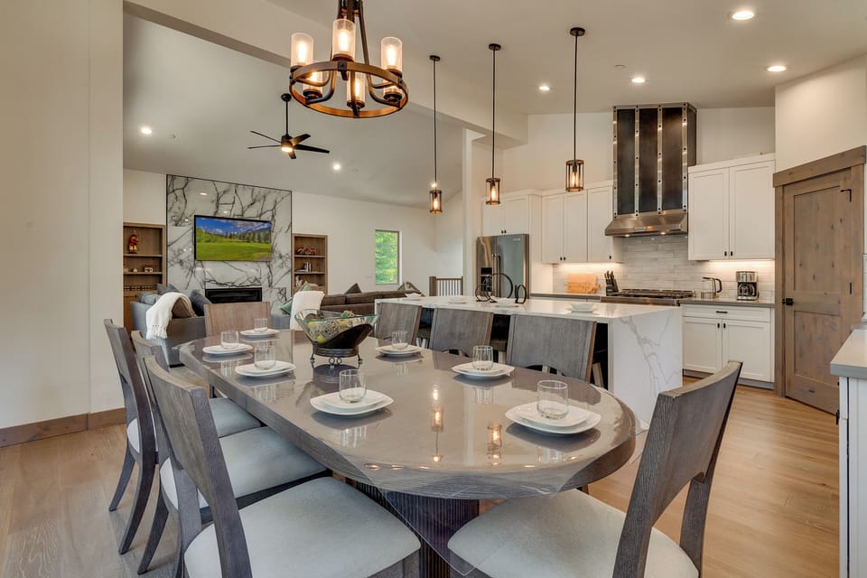 Dining table set for eight, with the kitchen and living area in the background