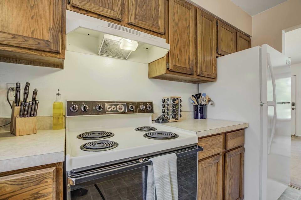 The kitchen is stocked with everyday essentials, including an electric stove, spice rack, utensils, and knife set—everything you need for easy at-home meals.

