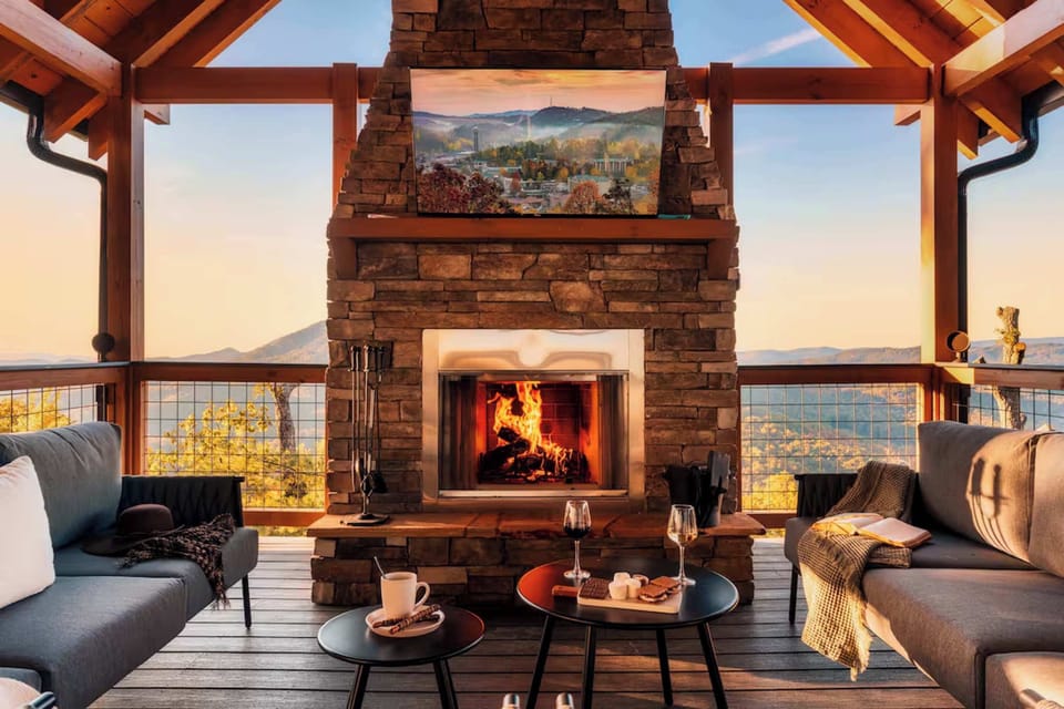 Cozy outdoor seating area with a stone fireplace and mountain views at sunset.