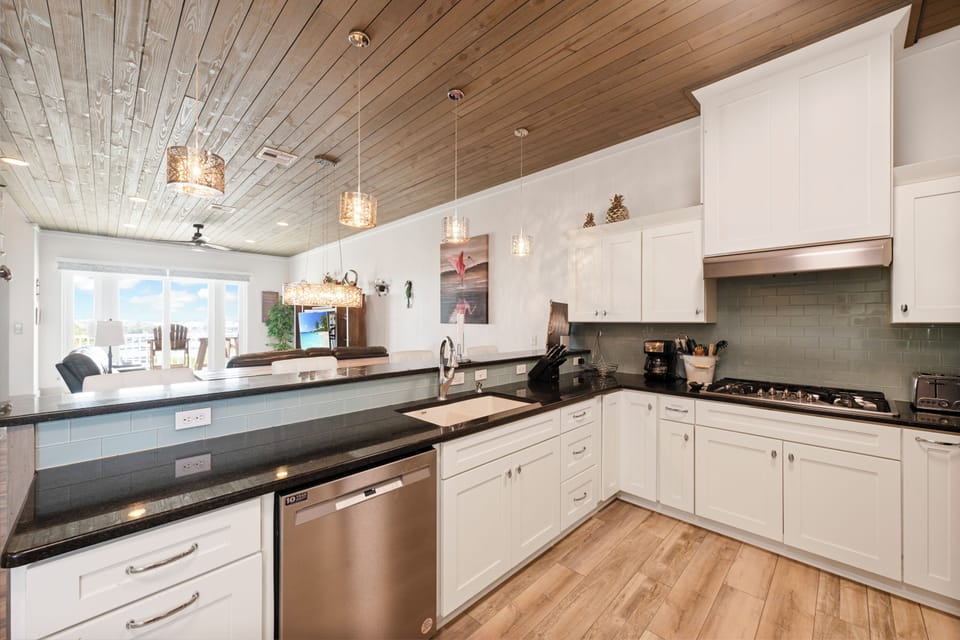 Your fully equipped chef's kitchen awaits with sleek granite counters, modern appliances, and warm wood ceiling.