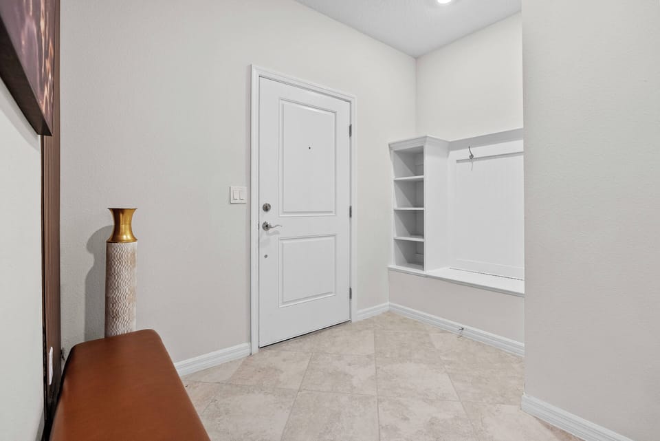 Welcome to a cozy entryway with soft beige carpeting and a sleek white door, creating an inviting atmosphere. Enjoy the stylish built-in shelving and contemporary decor that enhance your stay with comfort and sophistication.