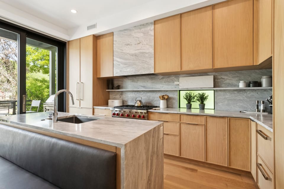 a large chefs kitchen with marble counter tops, lots of modern style storage and a gourmet gas oven