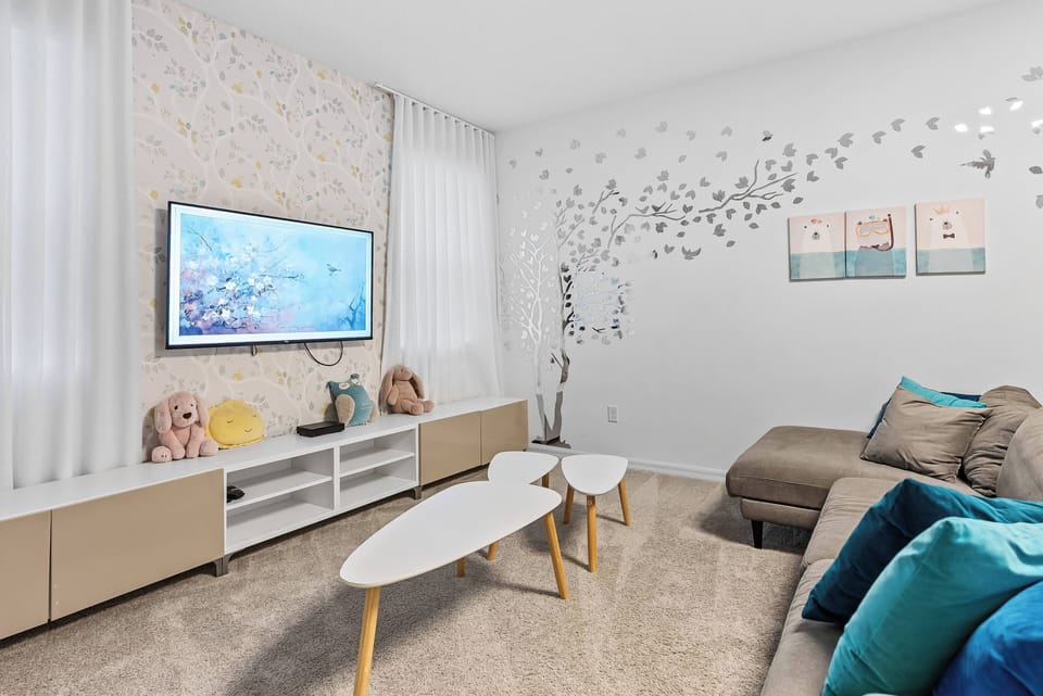 Relax in this stylish living area with a plush sectional sofa and vibrant teal pillows, perfect after a day of adventure. Enjoy the sleek coffee table and modern entertainment unit, accented by soft drapes and decorative wall art.