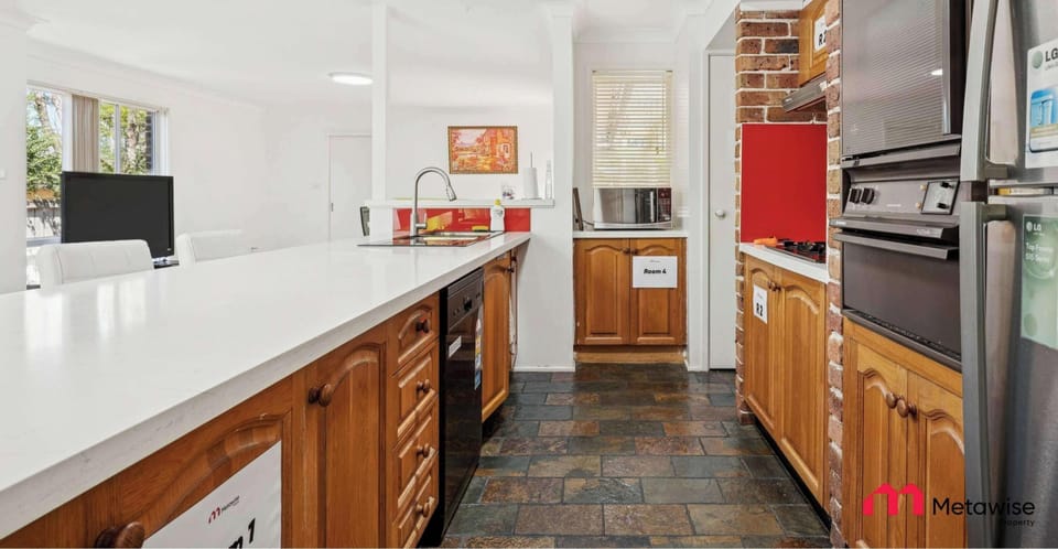 Shared kitchen with long countertop, wooden cabinetry, and cooking appliances.