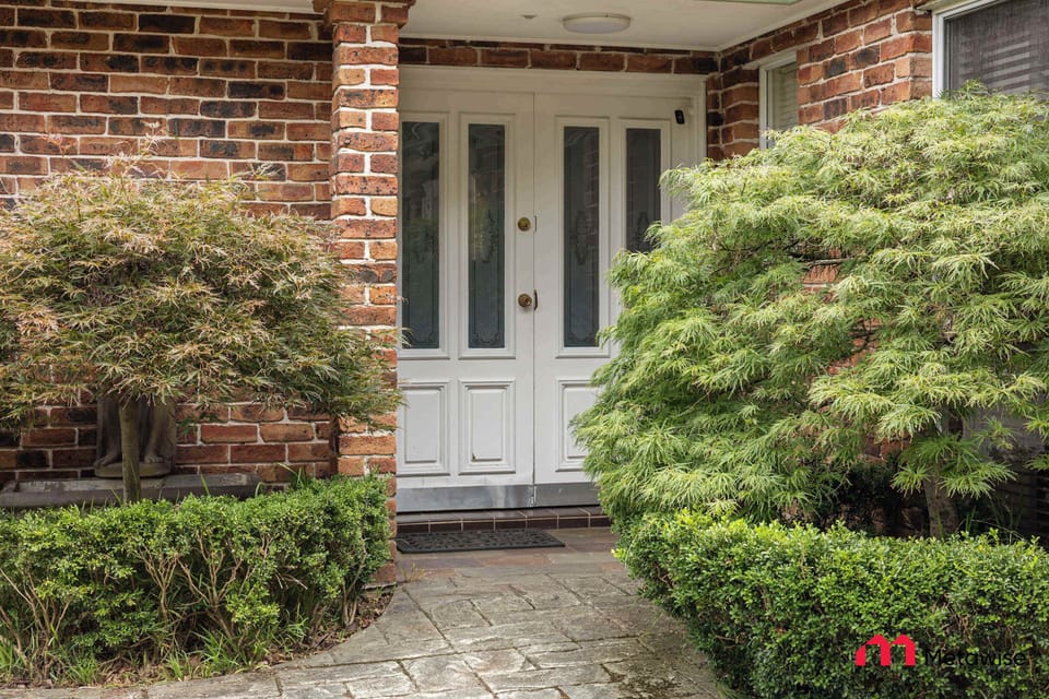 Welcoming front entrance with brick façade and neatly trimmed hedges.