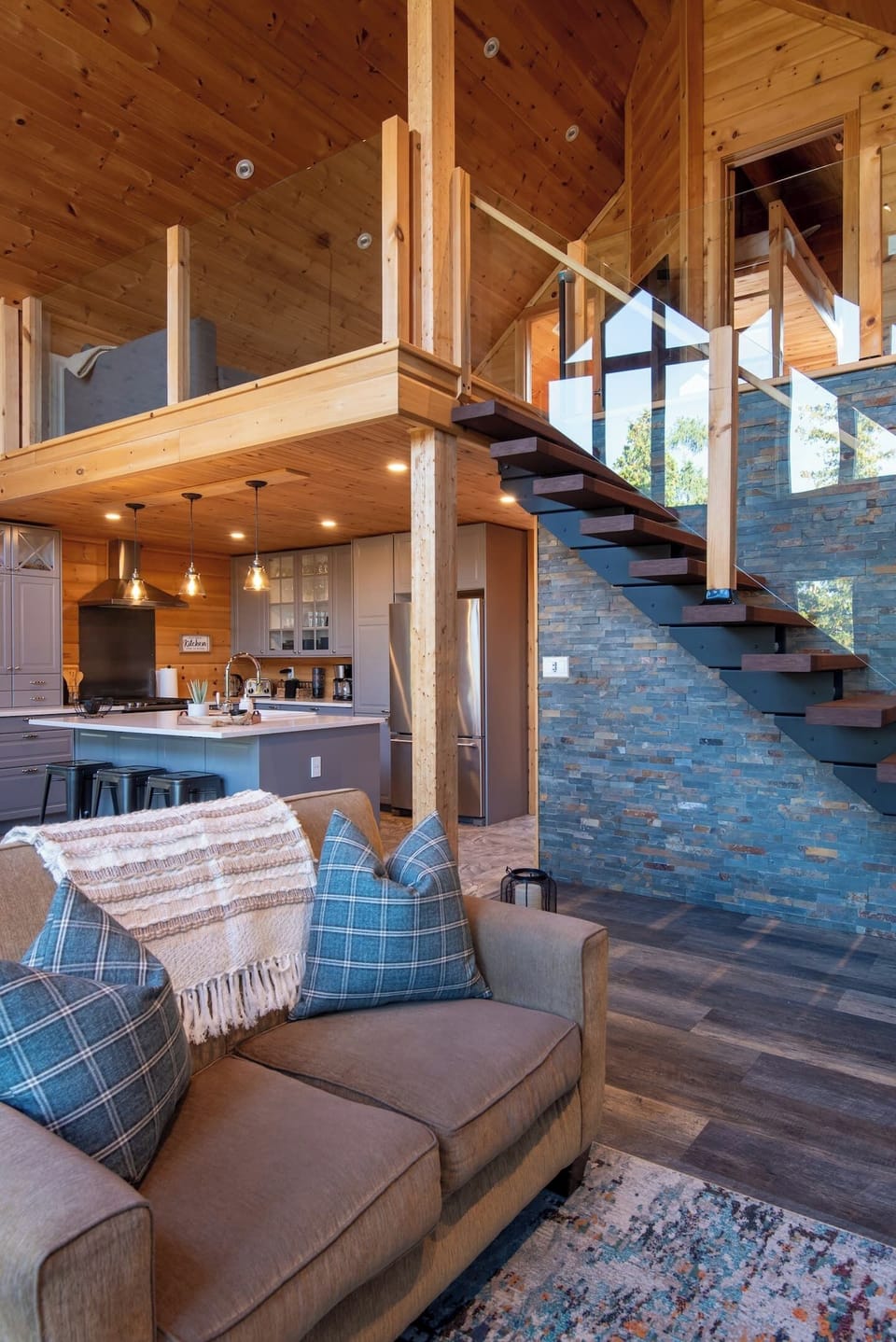 Stunning open-concept design—modern kitchen, cozy living area, and striking stone feature wall all in one view.
