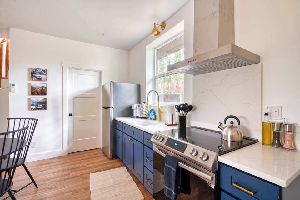 Blue-cabinet kitchen with stainless range and marble backsplash.