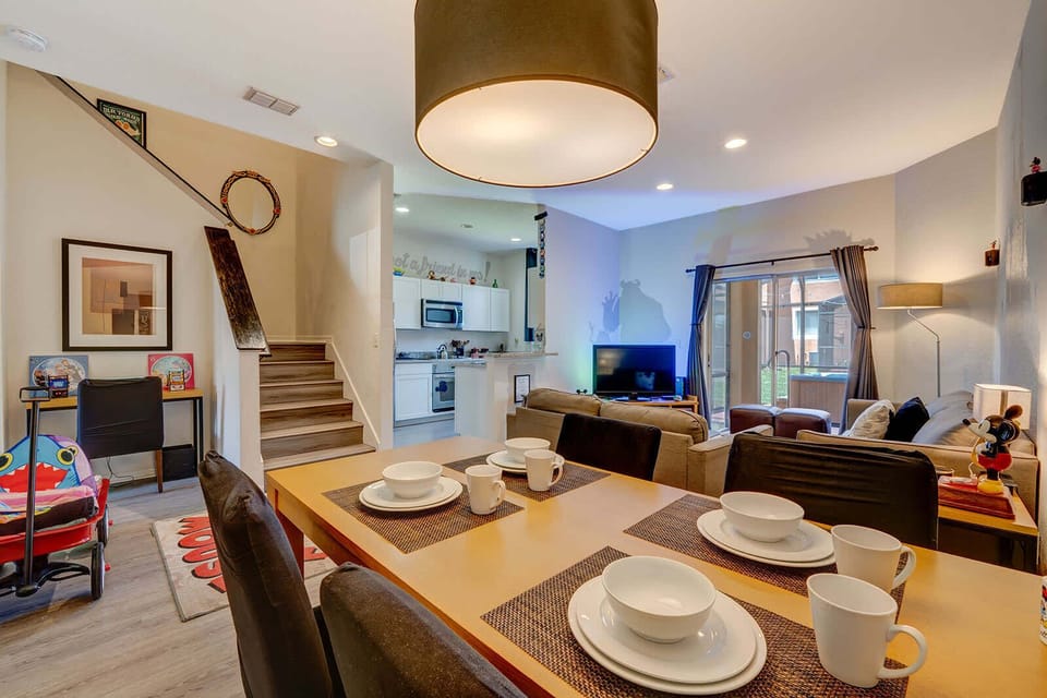 Open dining and living area with modern lighting and a view of the kitchen and staircase