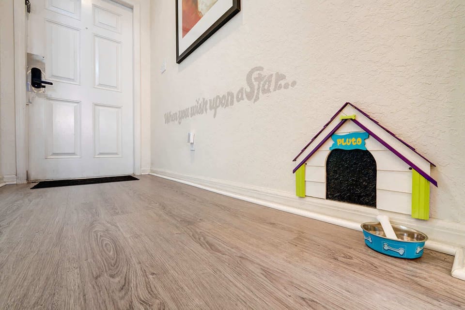 Entryway featuring a playful dog house nook with a bone and water bowl on wood flooring.
