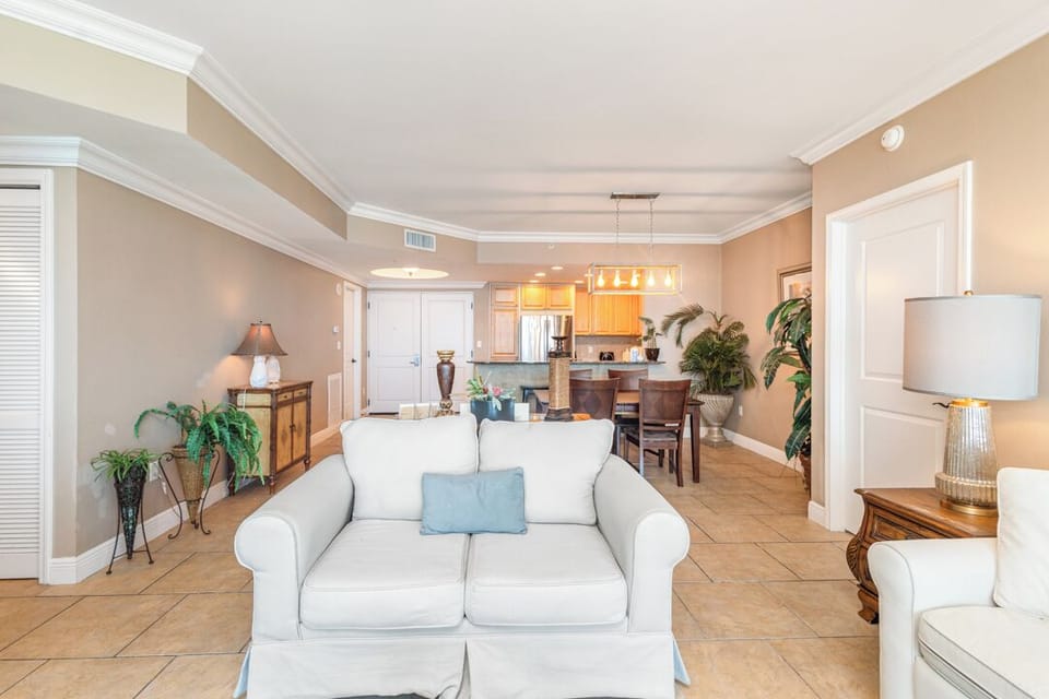 Unwind in your open-concept living space where soft coastal colors and comfortable seating invite you to relax. Natural light fills the room, connecting living, dining, and kitchen areas for effortless vacation living.