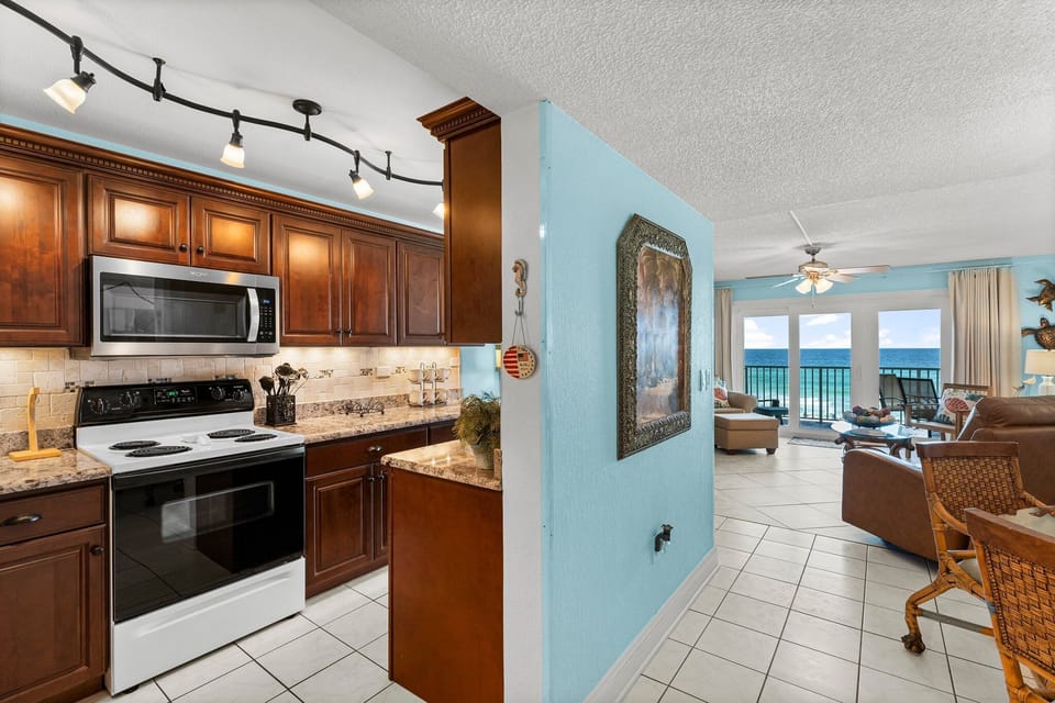 Kitchen w/ dark wood cabinets, granite counters, & stainless steel appliances — ready for home-cooked meals.