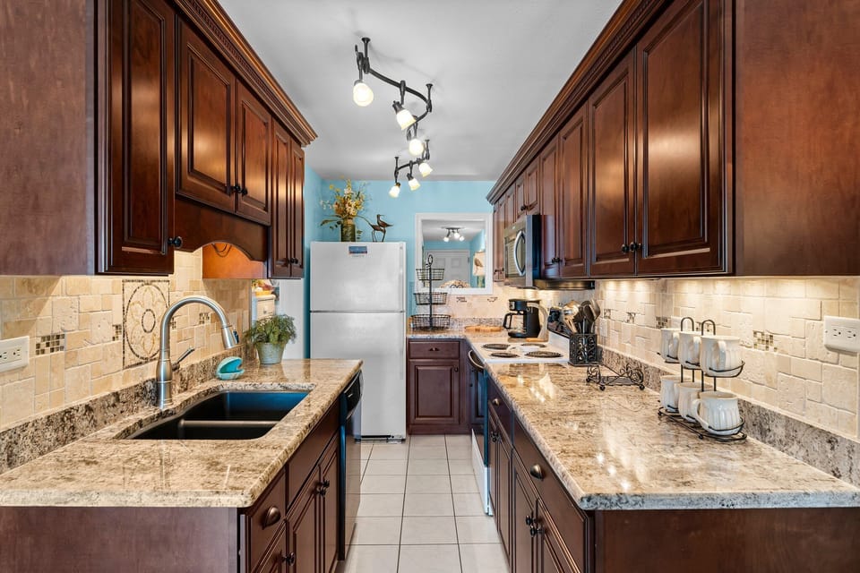 Fully equipped kitchen w/ dark wood cabinets, granite counters, & modern appliances.