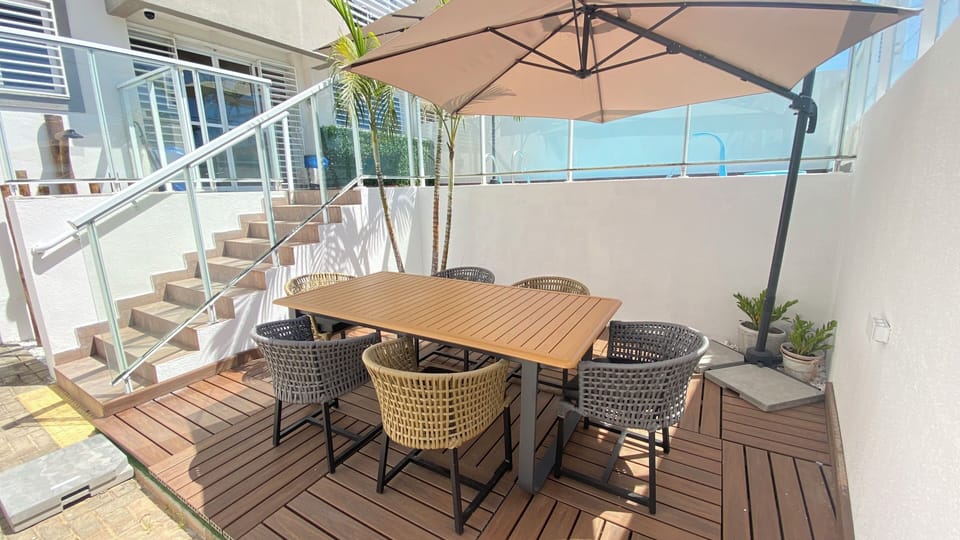 Outdoor dining and a bbq grill on this patio. Umbrella provides shade.