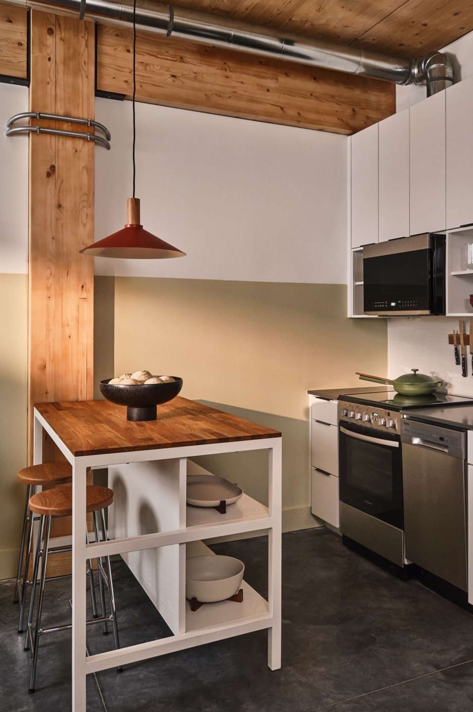 Wooden kitchen island with stools near oven and fridge