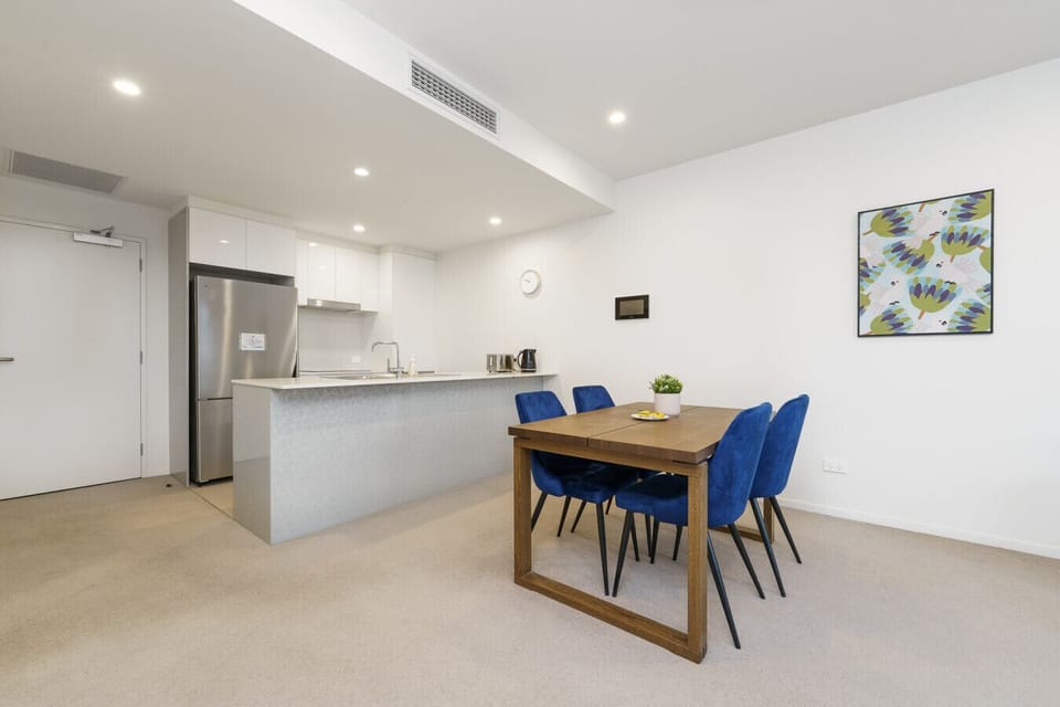 Contemporary eating area: four blue chairs around a solid wood table, plus handy kitchen access.