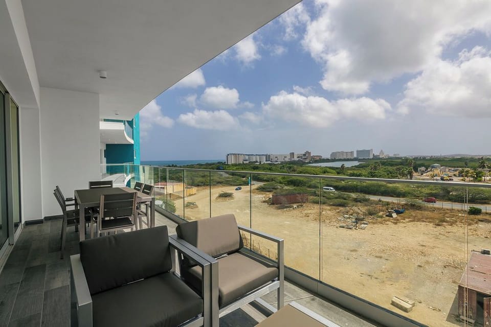 Modern balcony overlooking distant coastal views and natural landscape, featuring contemporary outdoor furniture for relaxing above the surrounding area.