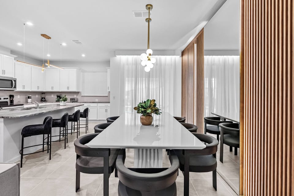 Enjoy a stylish dining space with a sleek marble table and comfortable black chairs, ideal for gatherings. The pendant lighting creates a warm ambiance, complemented by elegant curtains for an inviting atmosphere.