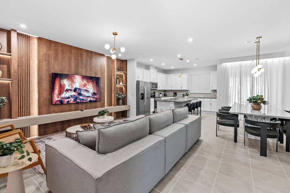 Enjoy a stylish living area where a warm wood accent wall complements modern furnishings. Large windows fill the space with natural light, and a cozy fireplace creates a perfect atmosphere for relaxing evenings.